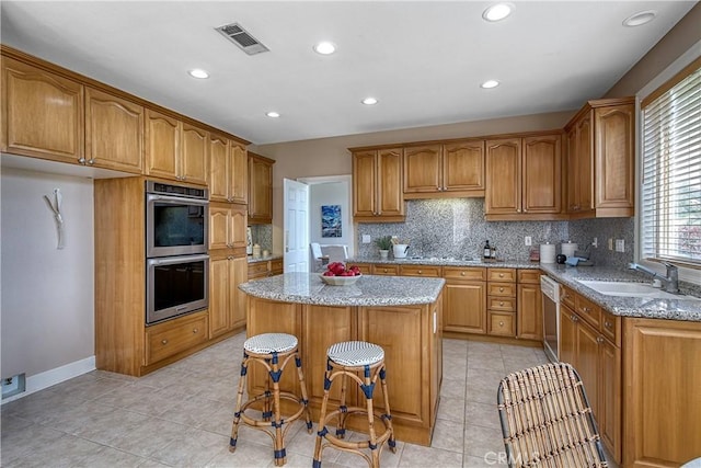 24932 Normans Way, Calabasas, CA 91302 - kitchen featuring double oven, a center island, brown cabinetry, light stone countertops, and recessed lighting