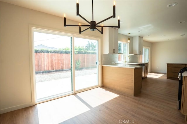 5808 Adele Ave, Whittier, CA 90606 - kitchen featuring baseboards, a peninsula, decorative backsplash, a sink, and wood finished floors