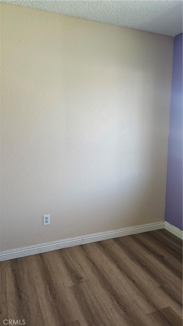 unfurnished room featuring dark wood finished floors and baseboards