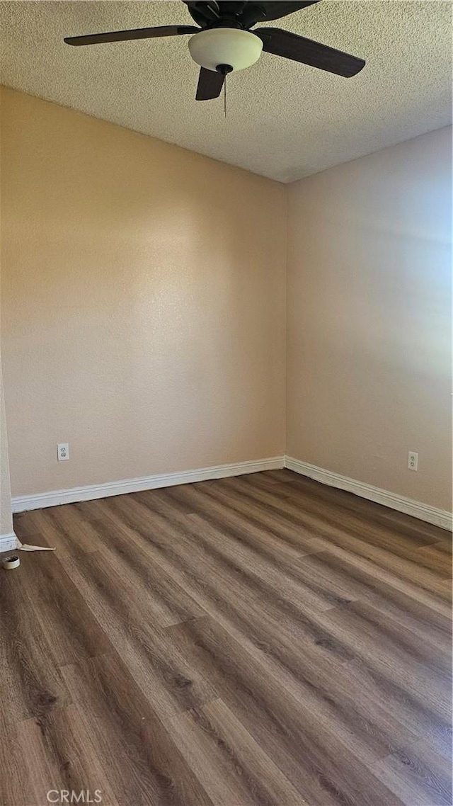 unfurnished room featuring dark wood-type flooring, a textured ceiling, baseboards, and ceiling fan