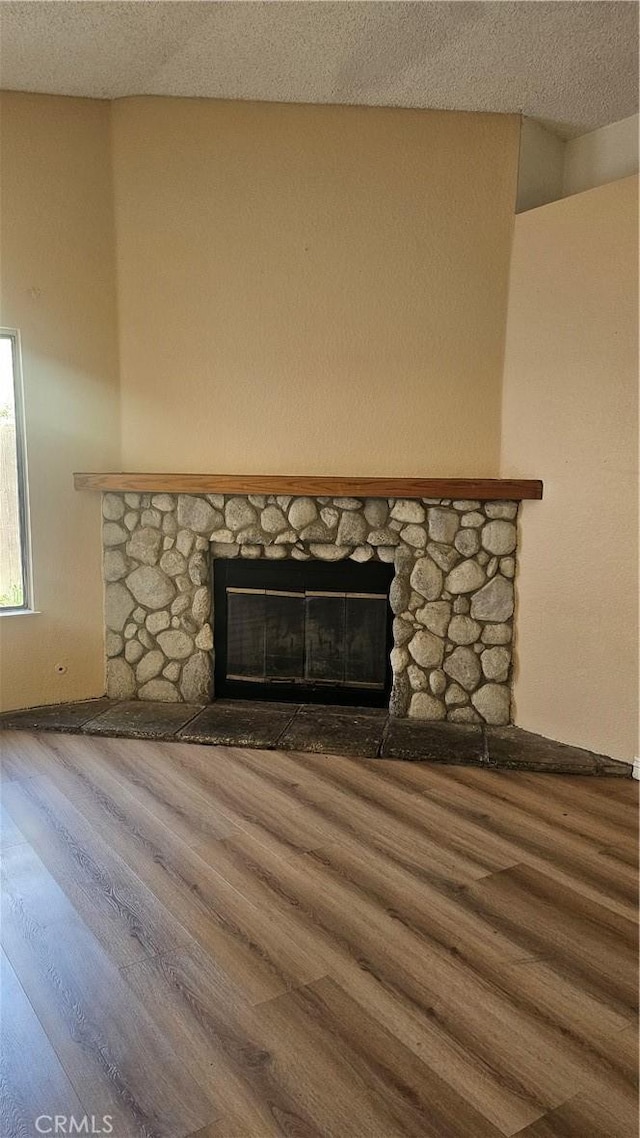details featuring a fireplace, wood finished floors, a textured ceiling, and baseboards