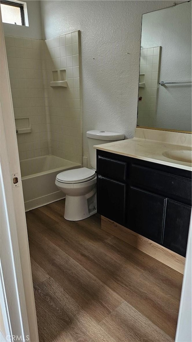 full bathroom with wood finished floors, toilet, vanity, and a textured wall