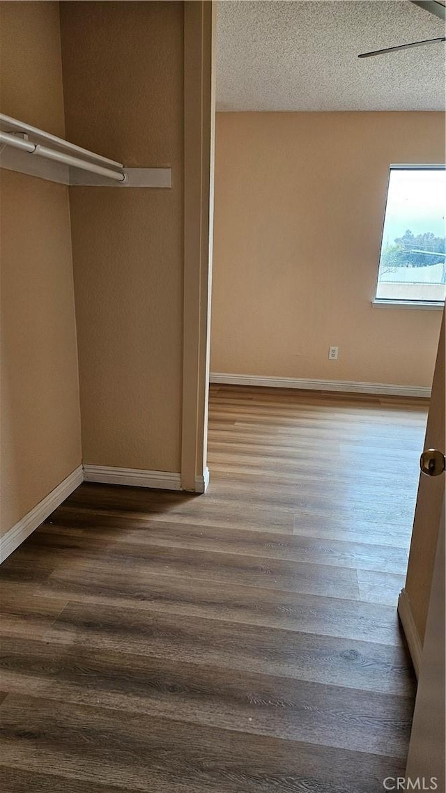 unfurnished bedroom with wood finished floors, a textured ceiling, and baseboards