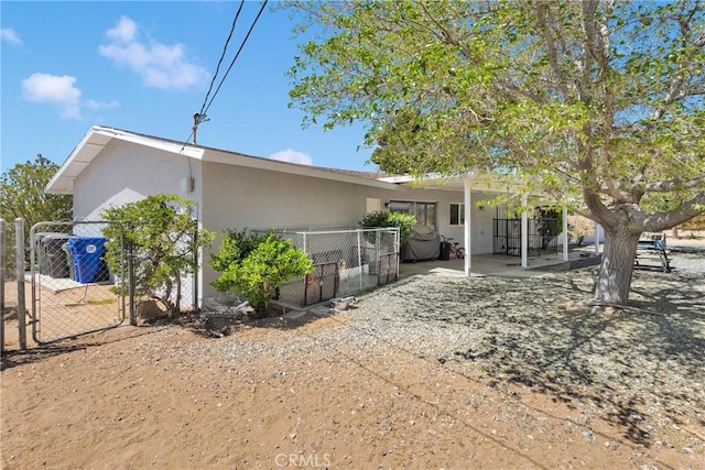 exterior space featuring fence, a gate, stucco siding, and a patio area