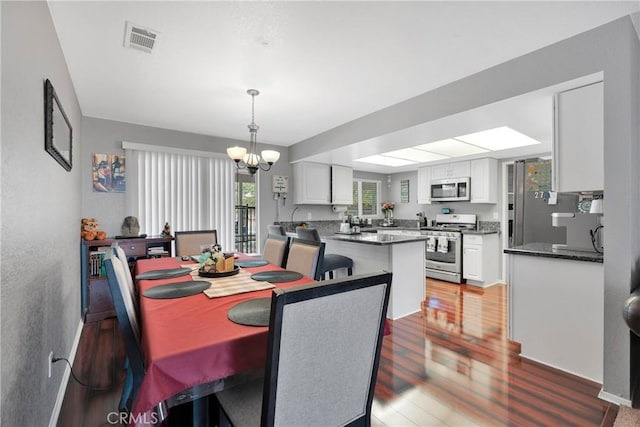 dining space with visible vents, wood finished floors, and an inviting chandelier