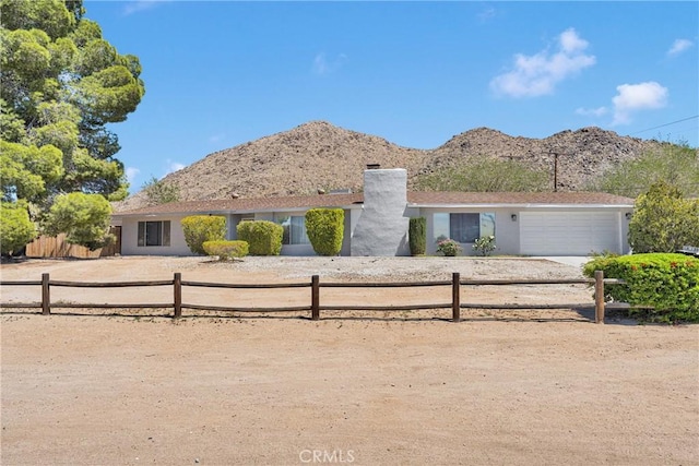 single story home featuring an attached garage, fence private yard, a chimney, and a mountain view