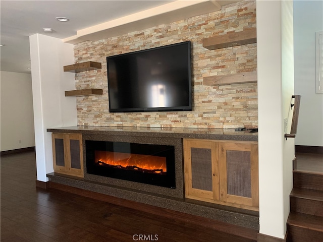 room details with baseboards, wood finished floors, and a glass covered fireplace