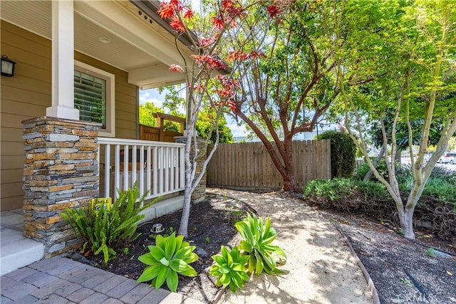 view of patio featuring fence and a porch