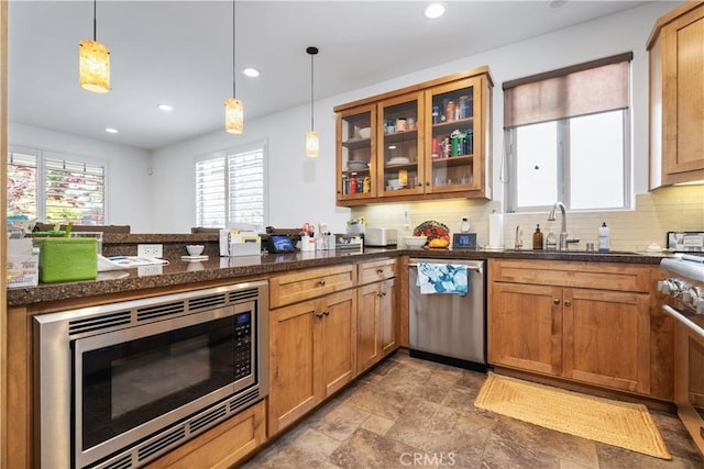 kitchen with recessed lighting, a sink, decorative backsplash, decorative light fixtures, and appliances with stainless steel finishes