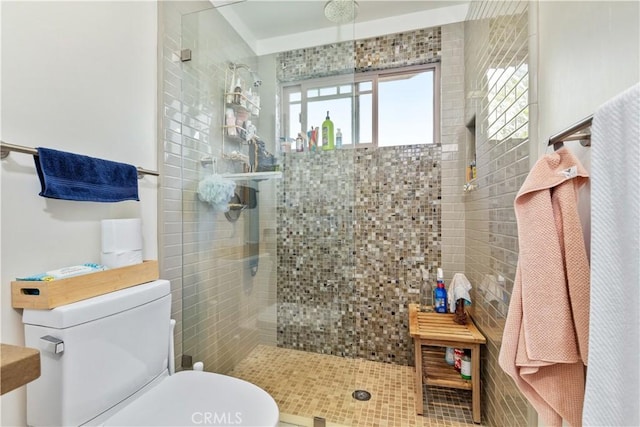 bathroom featuring tiled shower and toilet
