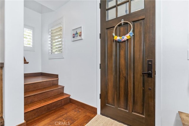 foyer with baseboards, stairway, and wood finished floors