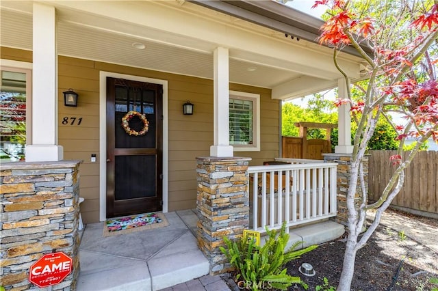 property entrance with fence and a porch
