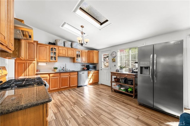 kitchen featuring a sink, light wood-style floors, lofted ceiling with skylight, stainless steel appliances, and pendant lighting