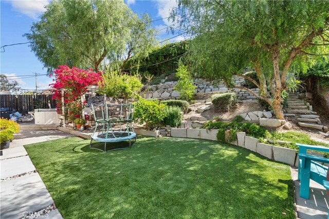 view of yard with a trampoline and fence