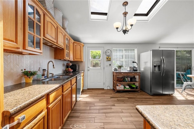 kitchen featuring stainless steel appliances, glass insert cabinets, light wood-type flooring, and a sink