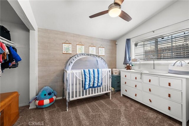 bedroom featuring dark carpet, vaulted ceiling, a nursery area, and ceiling fan