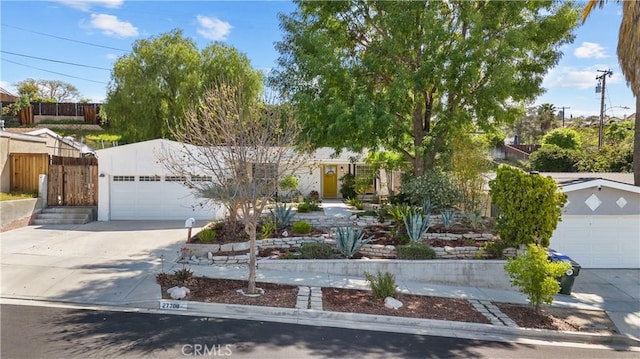view of front facade with a garage, fence, driveway, and stucco siding