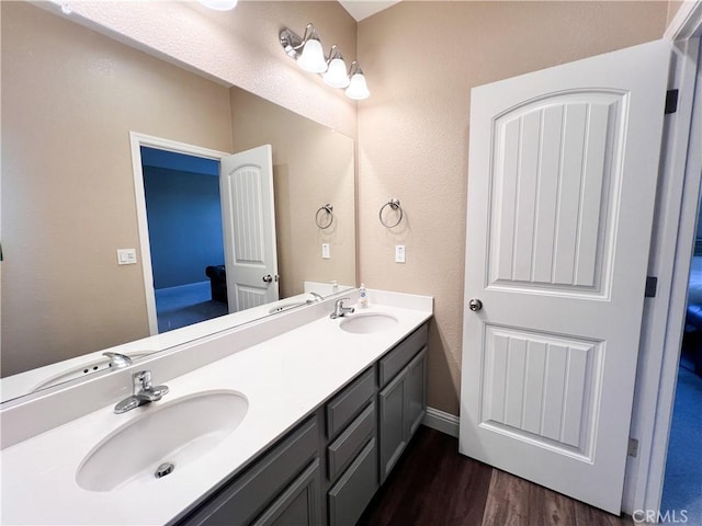 full bath featuring a sink, double vanity, and wood finished floors