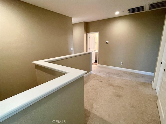 hallway featuring visible vents, baseboards, recessed lighting, and light colored carpet
