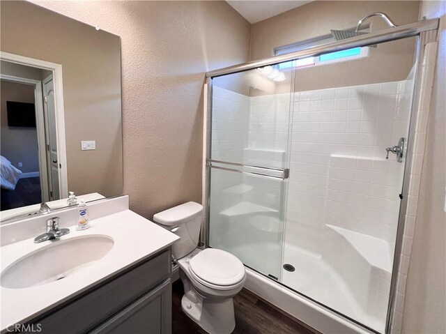 full bath with a shower stall, vanity, toilet, and a textured wall