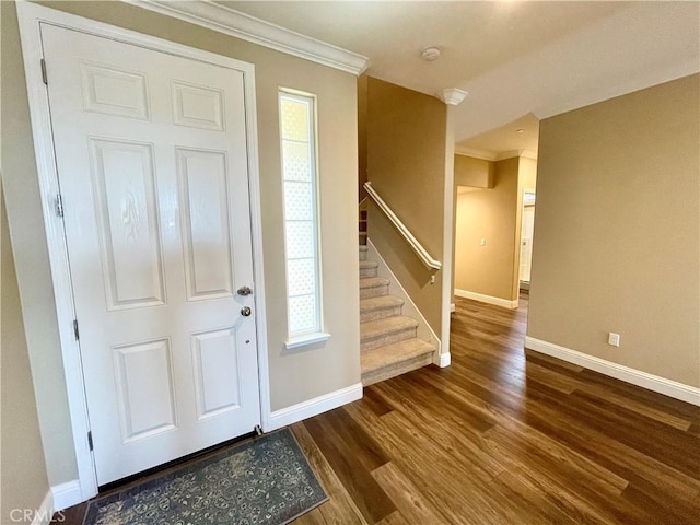 foyer entrance featuring stairs, dark wood-type flooring, baseboards, and ornamental molding