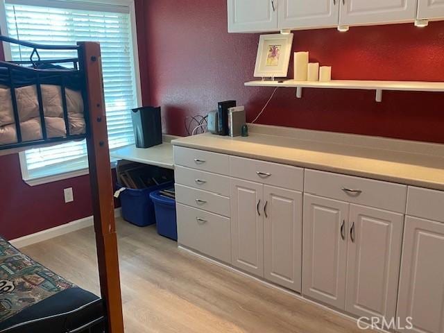 kitchen featuring light wood-type flooring, a healthy amount of sunlight, and white cabinets