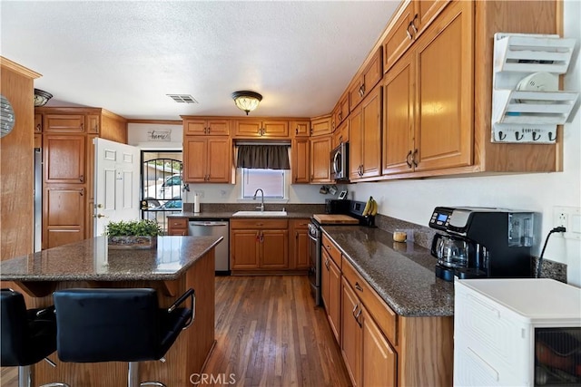 22432 Van Buren St, Grand Terrace, CA 92313 - kitchen featuring dark wood finished floors, visible vents, a sink, brown cabinets, and stainless steel appliances
