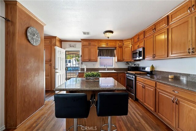 22432 Van Buren St, Grand Terrace, CA 92313 - kitchen with a sink, brown cabinets, dark wood-type flooring, visible vents, and appliances with stainless steel finishes