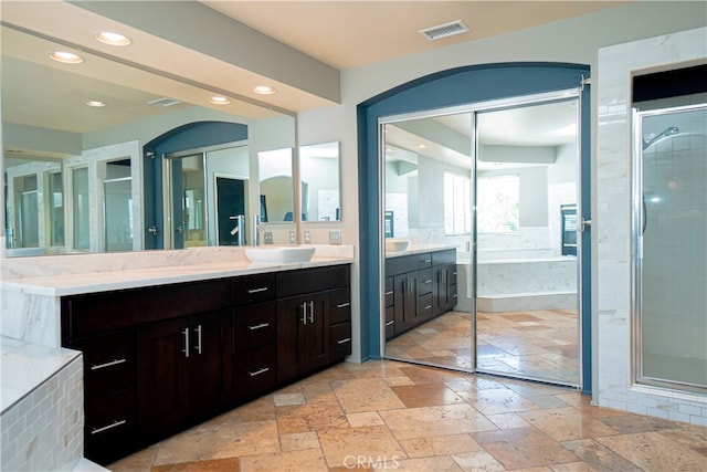 full bathroom with a stall shower, stone tile floors, vanity, and visible vents