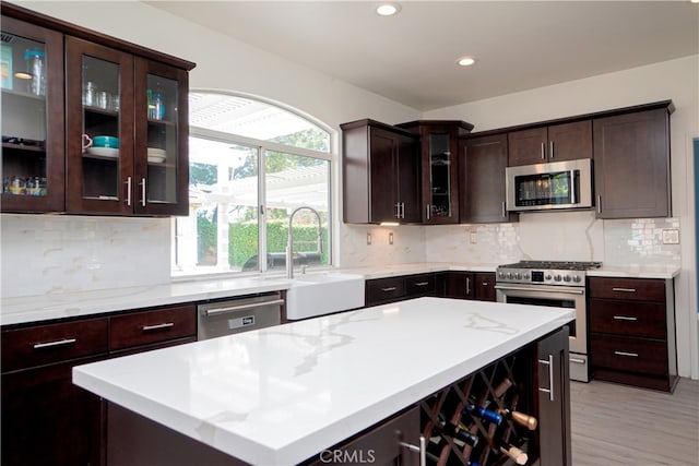 kitchen with a sink, appliances with stainless steel finishes, dark brown cabinets, recessed lighting, and backsplash