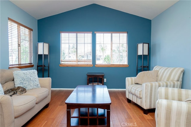 living area featuring lofted ceiling, baseboards, and wood finished floors