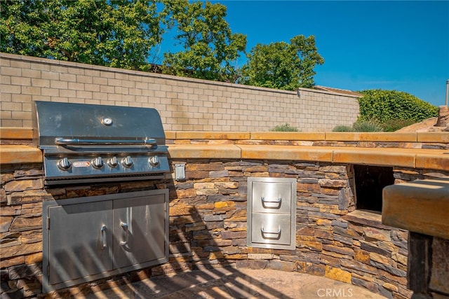 view of patio / terrace featuring exterior kitchen, a grill, and fence