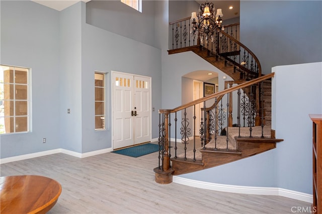 foyer entrance with wood finished floors, a towering ceiling, and baseboards