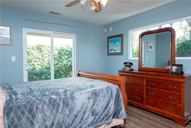 bedroom with a ceiling fan, wood finished floors, multiple windows, and visible vents