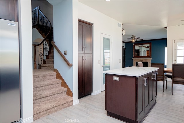 kitchen with a center island, light wood finished floors, high end fridge, and dark brown cabinetry
