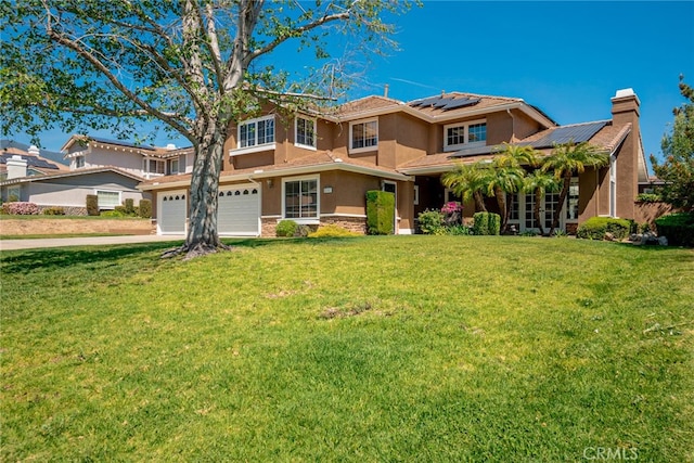 view of front of house featuring roof mounted solar panels, a garage, concrete driveway, a front lawn, and stucco siding