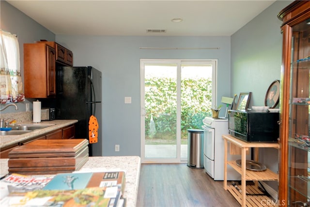 kitchen featuring a sink, light countertops, visible vents, black appliances, and wood finished floors