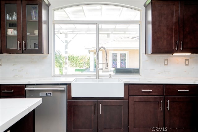 kitchen featuring tasteful backsplash, stainless steel dishwasher, a sink, and dark brown cabinetry