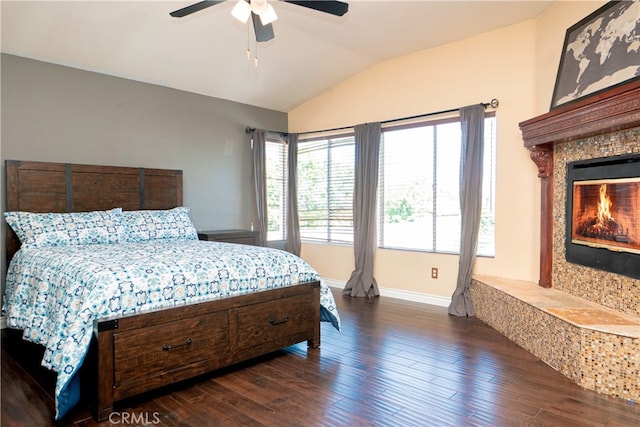 bedroom with baseboards, a ceiling fan, dark wood-style floors, a fireplace, and lofted ceiling