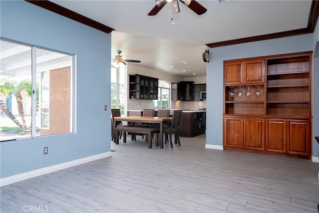 dining area with light wood-style floors, baseboards, a ceiling fan, and crown molding