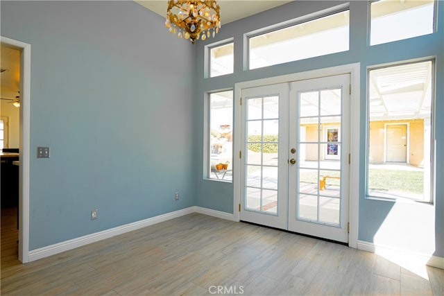 doorway featuring french doors, wood finished floors, baseboards, and a chandelier