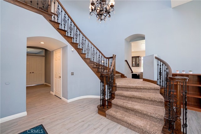 stairway featuring arched walkways, a high ceiling, and wood finished floors