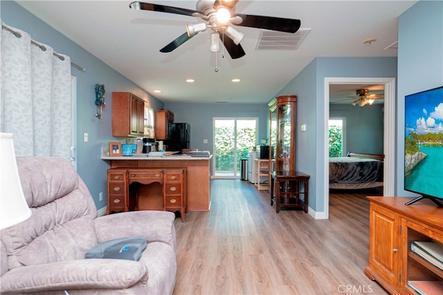 living room featuring light wood-style flooring, a ceiling fan, visible vents, and plenty of natural light