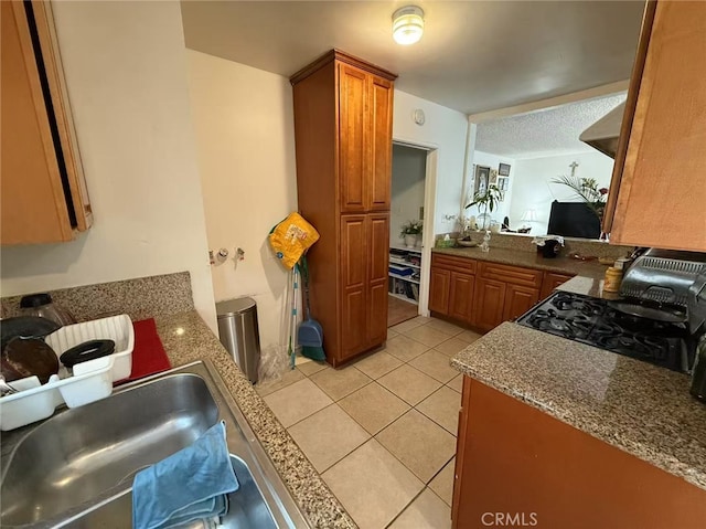 745 S Chapel Ave, Alhambra, CA 91801 - kitchen with black range with gas stovetop, light tile patterned flooring, brown cabinetry, and a sink