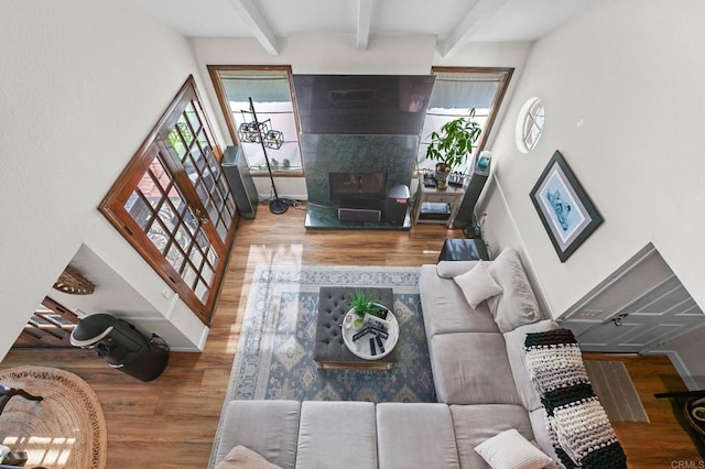living room with wood finished floors, beam ceiling, and plenty of natural light