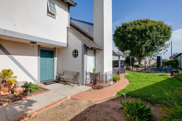 property entrance with stucco siding, a patio, and a yard