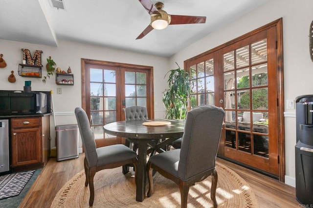 dining room with french doors, healthy amount of natural light, ceiling fan, and light wood-type flooring