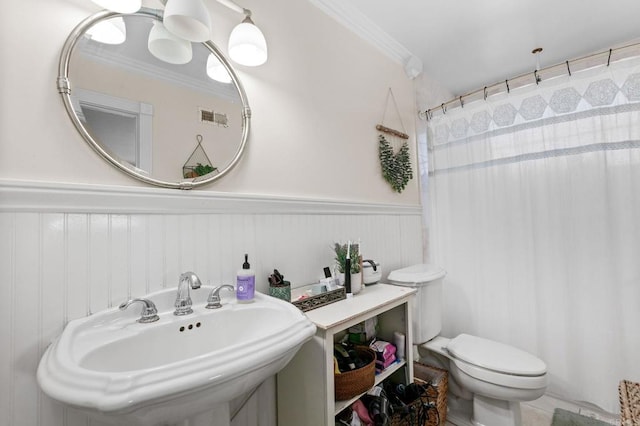 bathroom with ornamental molding, a sink, a wainscoted wall, toilet, and curtained shower