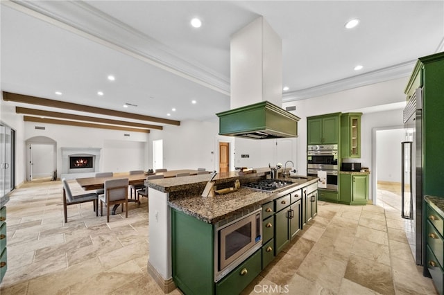 kitchen featuring stainless steel appliances, a kitchen island with sink, ornamental molding, and green cabinets