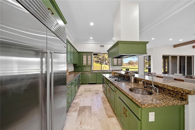 kitchen with green cabinetry, a sink, appliances with stainless steel finishes, island exhaust hood, and an island with sink